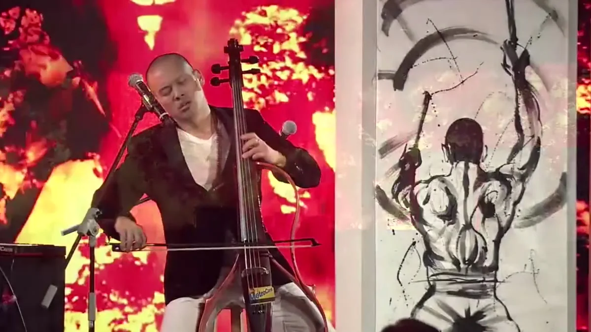 Dana Leong playing electric cello against a vast sun projection with sumi-e panels at Summer Davos in Dalian