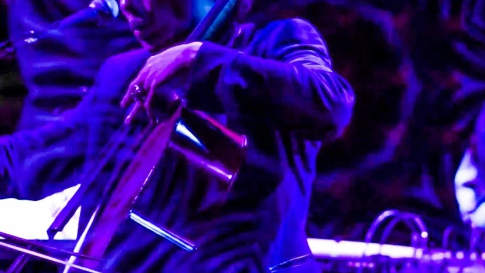 Dana Leong bowing his electric cello under deep purple stage light during Reflections at Joe’s Pub, New York