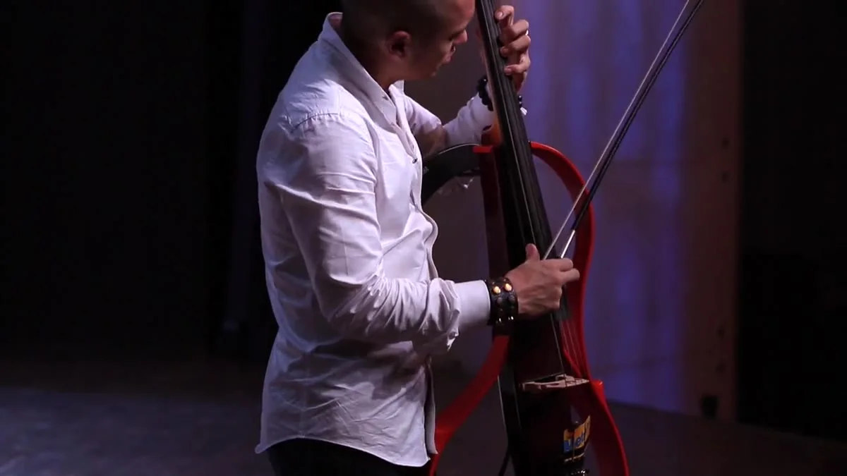 Dana Leong playing his red electric cello in low stage light at Mercedes-Benz Arena, Shanghai